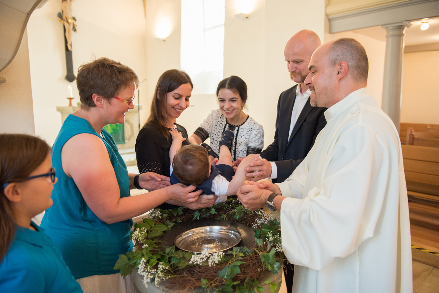 Kind wird am Taufbecken getauft